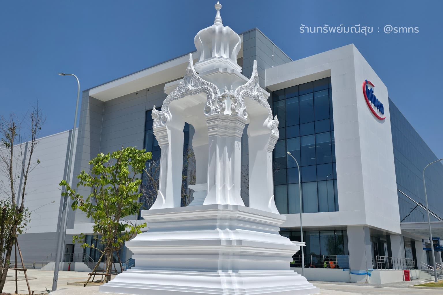 ศาลพระพรหมสีขาวของบริษัท Infineon มุมเฉียงหน้าอาคาร เห็นเสาสูง ซุ้มลายไทย และฐานศาล