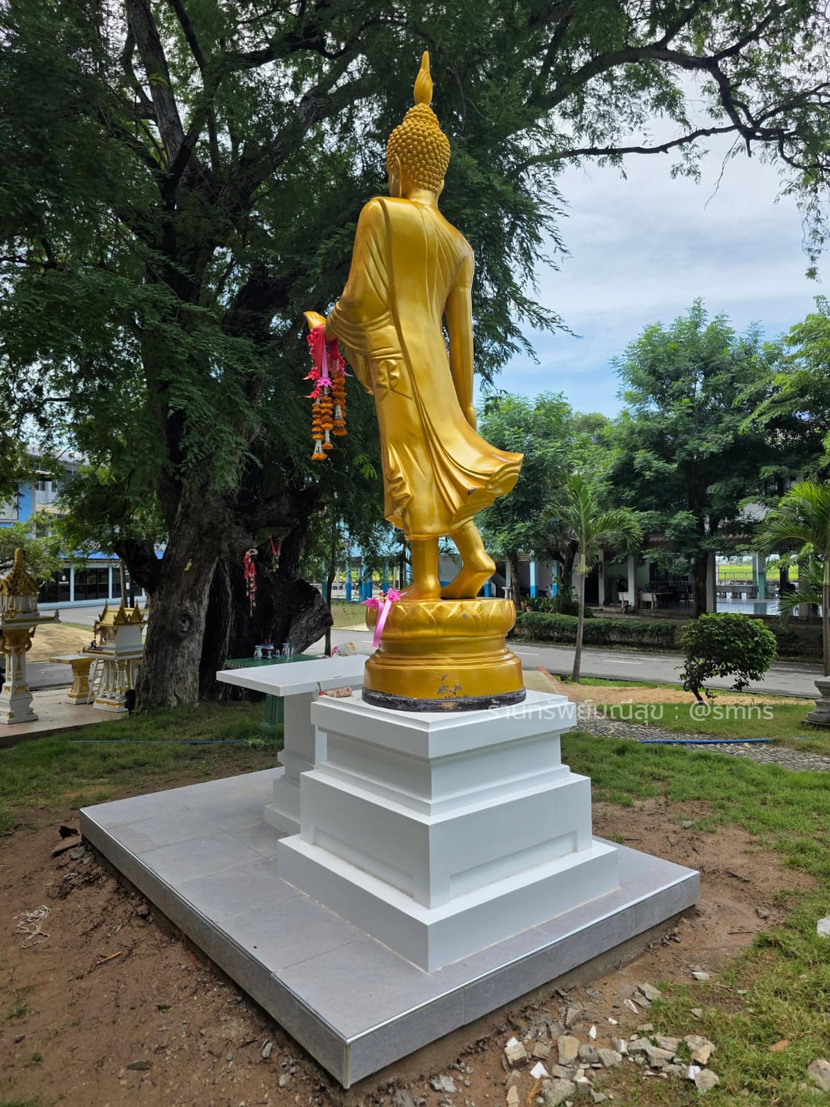 ฐานประดิษฐานสีขาวแบบลดหลั่น รองรับพระพุทธรูปปางประทานพรสีทอง มุมด้านหลัง